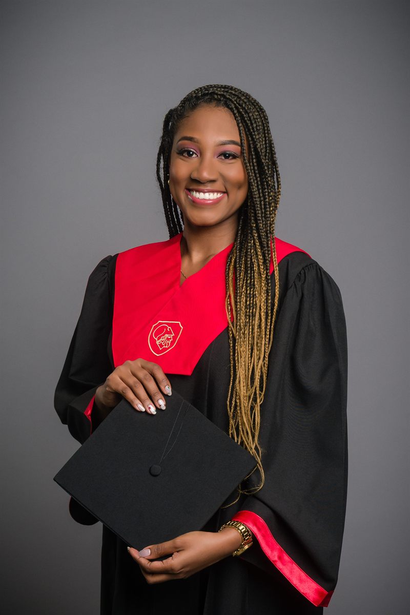 Graduada universitaria con birrete y trenzas, gran sonrisa